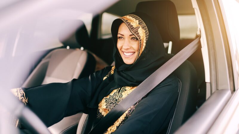 Muslim woman smiling and driving car