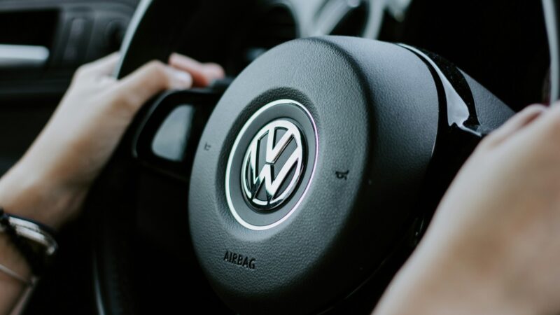 Hands on a steering wheel with Volkswagen logo