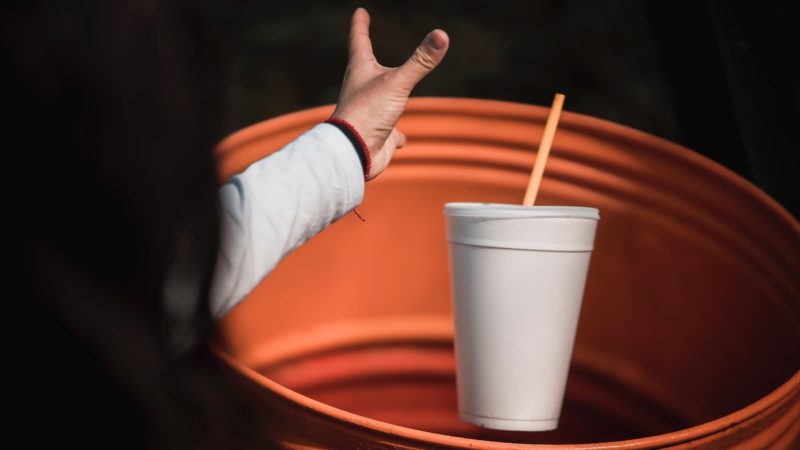 A woman throwing a styrofoam cup away