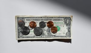 A dollar bill with assorted coins on top of it