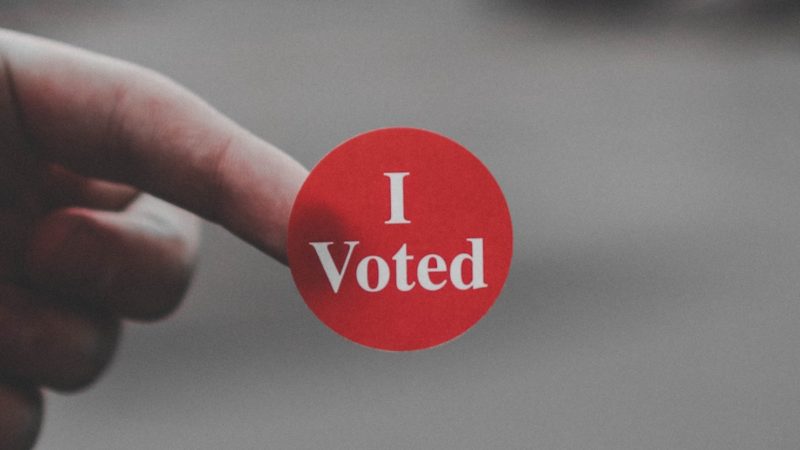 A person holding a sticker that says "I Voted"