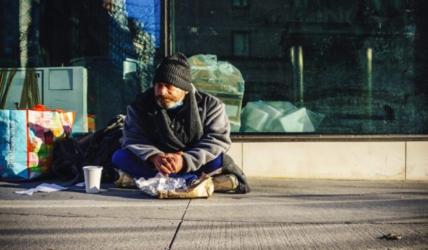 A homeless person sitting in front of the building