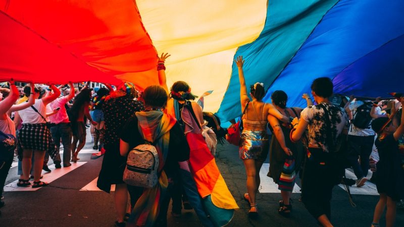 People holding up LGBTQ rainbow flag