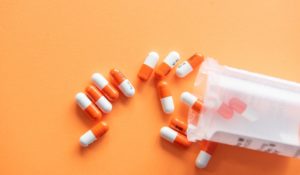 Prescription drugs on an orange background with a pill bottle. Orange pills.