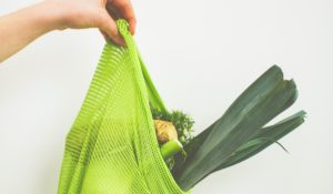 A person holding a bag full of vegetables