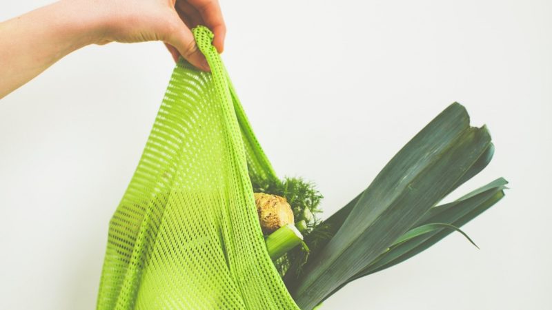 A person holding a bag full of vegetables