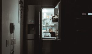 A refrigerator in a kitchen at night