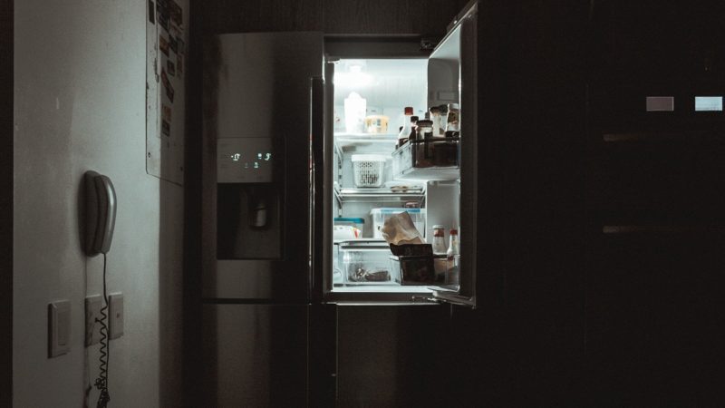 A refrigerator in a kitchen at night