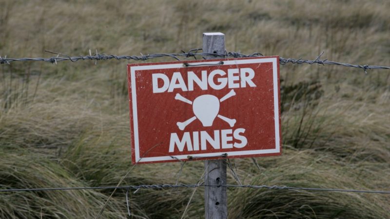 A Danger Mines sign on a barb wire fence
