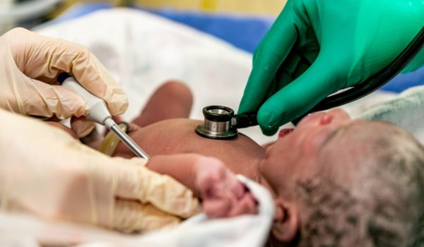 Newborn baby having lungs and body temperature checked