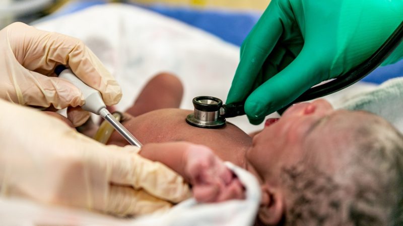 Newborn baby having lungs and body temperature checked