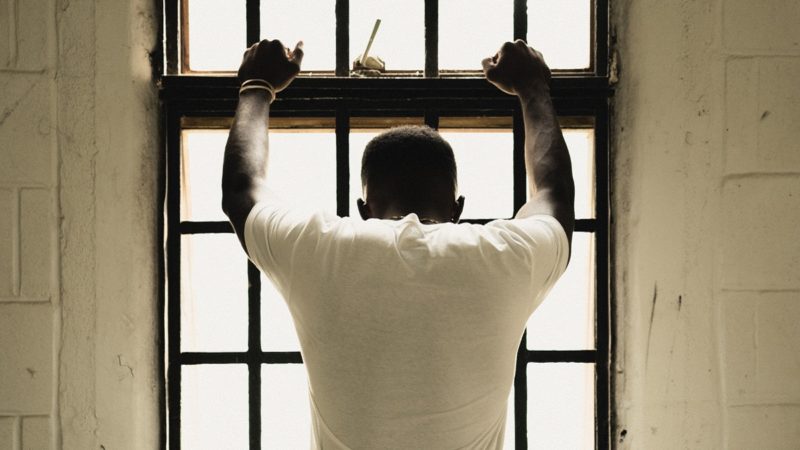Man holding on to prison bars