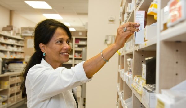 Pharmacist grabbing medicine off shelf