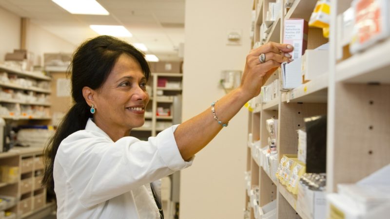 Pharmacist grabbing medicine off shelf