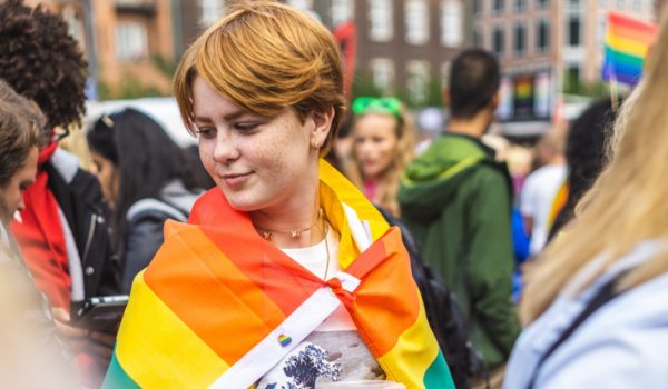 Young person with pride flag draped across back