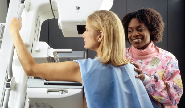 Woman receiving mammogram with support from another woman
