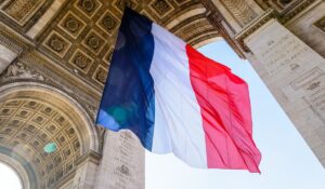 A large french flag fluttering under the Arc de Triomphe in Paris, France.