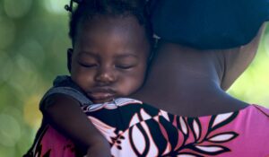 African girl sleeping on mother's shoulder