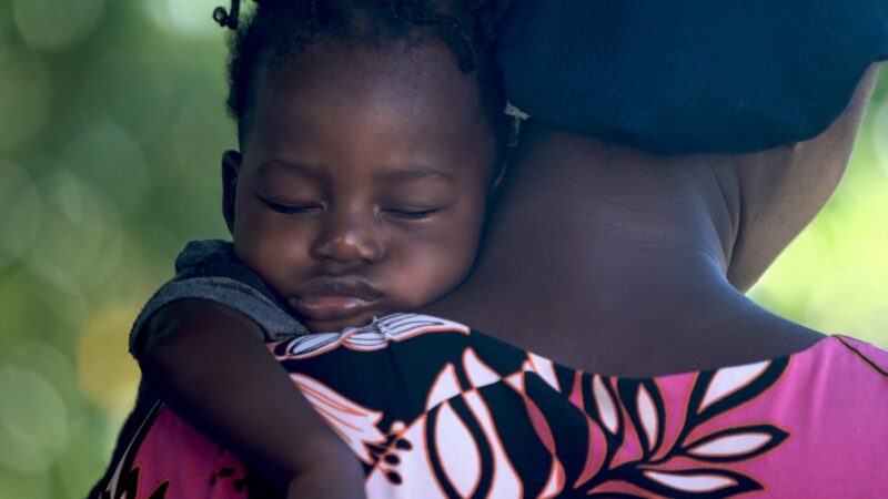 African girl sleeping on mother's shoulder